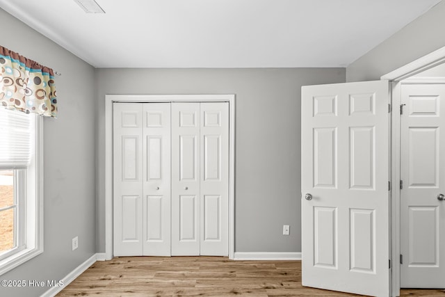 unfurnished bedroom with light wood-type flooring and a closet