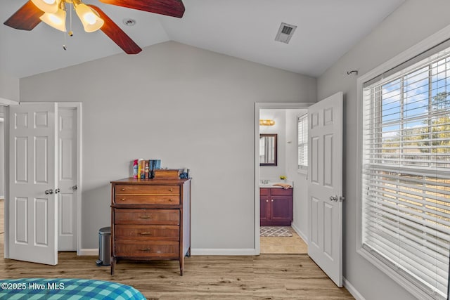 bedroom featuring ceiling fan, connected bathroom, multiple windows, and lofted ceiling