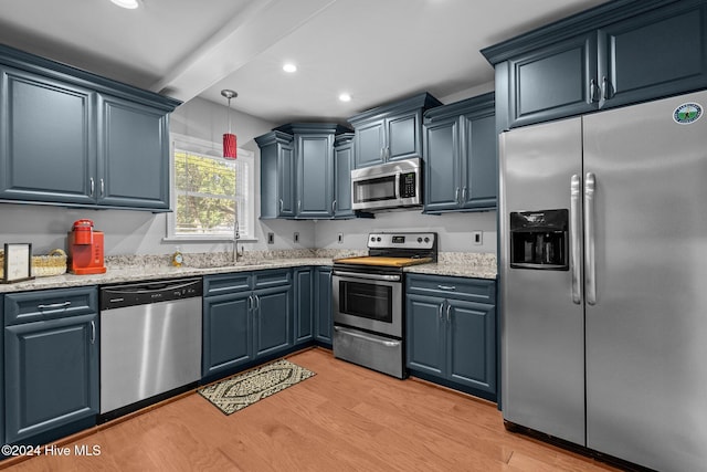 kitchen with blue cabinetry, sink, light stone counters, light hardwood / wood-style flooring, and appliances with stainless steel finishes