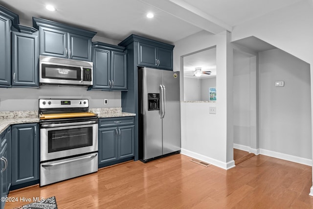 kitchen featuring light stone countertops, appliances with stainless steel finishes, ceiling fan, blue cabinetry, and light hardwood / wood-style floors