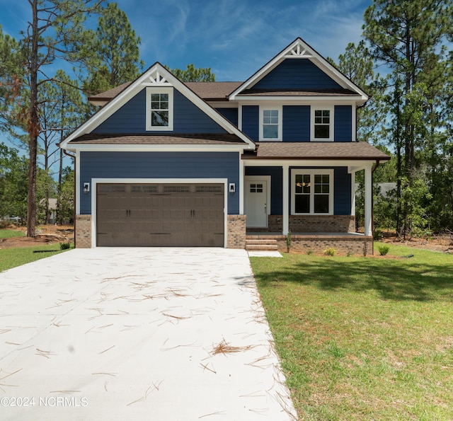 craftsman-style house featuring covered porch, a front yard, and a garage