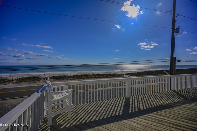 wooden deck featuring a water view and a beach view