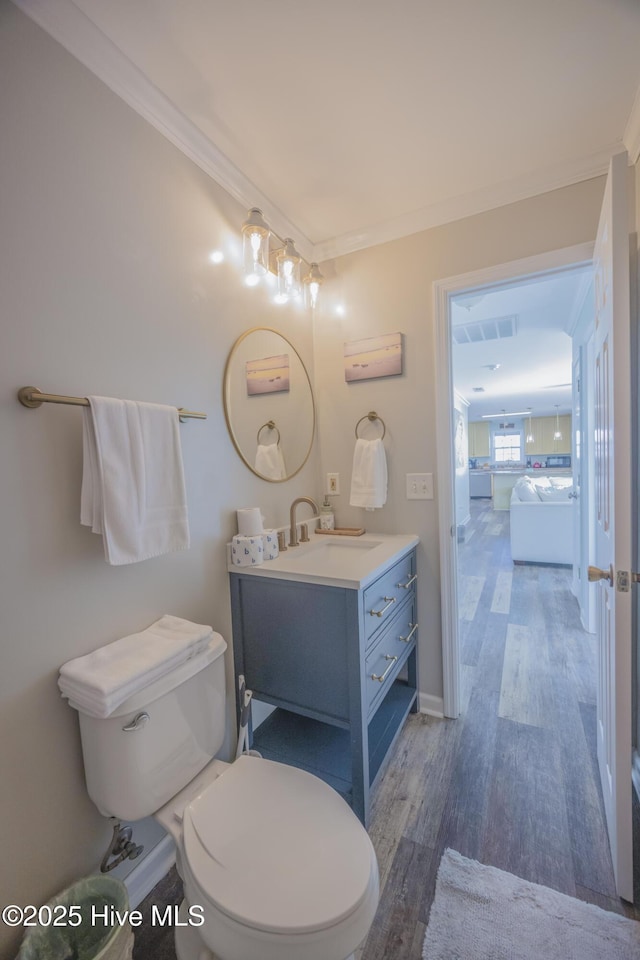 bathroom featuring wood-type flooring, vanity, toilet, and ornamental molding