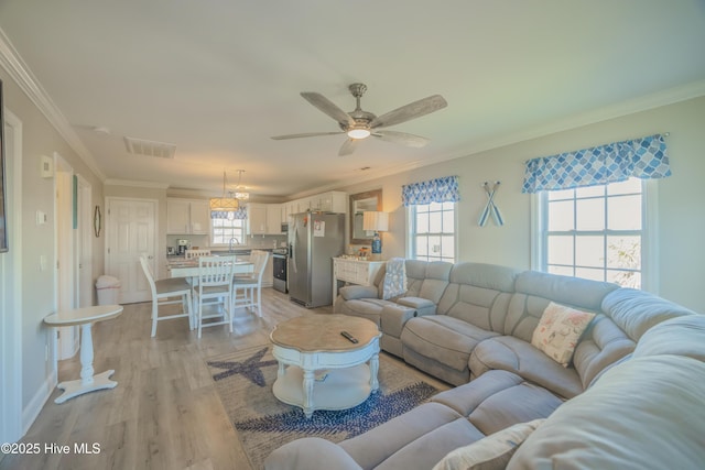 living room with ceiling fan, sink, crown molding, and light hardwood / wood-style flooring