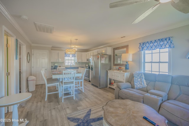 living room with ceiling fan, plenty of natural light, light hardwood / wood-style floors, and ornamental molding