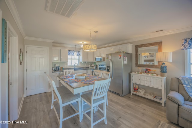 dining space with light wood-type flooring, crown molding, and sink