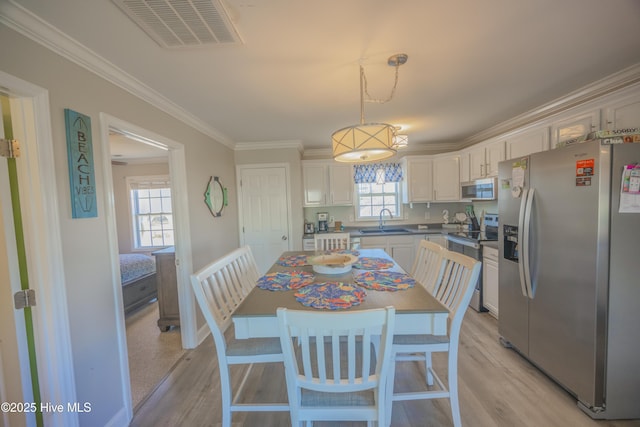 kitchen with stainless steel appliances, crown molding, sink, pendant lighting, and white cabinets