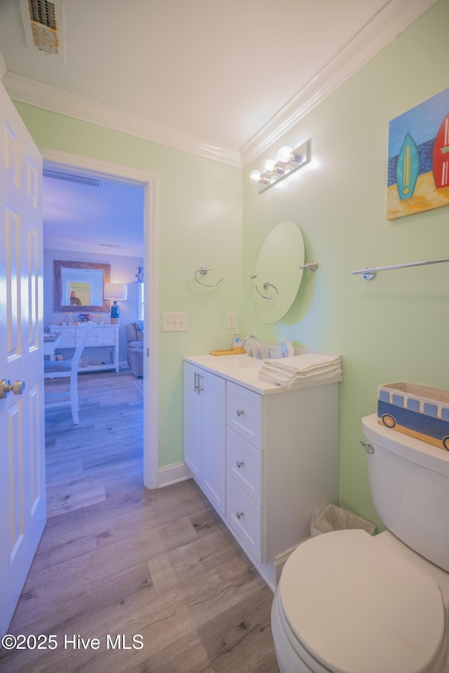 bathroom featuring hardwood / wood-style flooring, vanity, toilet, and crown molding