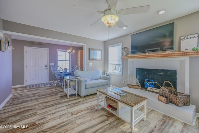 living room with ceiling fan with notable chandelier and light wood-type flooring