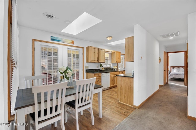 dining area with sink, light colored carpet, a skylight, and french doors