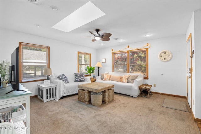 carpeted living room featuring ceiling fan and a skylight