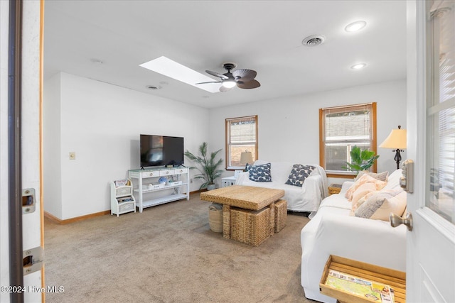 carpeted living room with ceiling fan, plenty of natural light, and a skylight