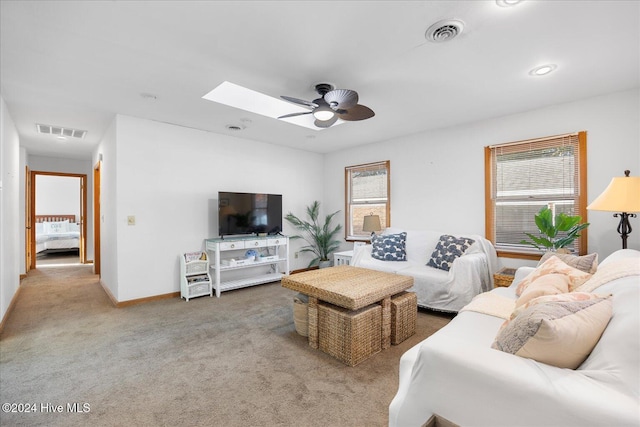 living room with a skylight, ceiling fan, and carpet floors