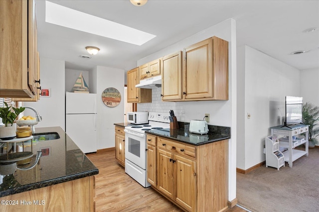 kitchen with white appliances, light brown cabinetry, a skylight, dark stone countertops, and backsplash