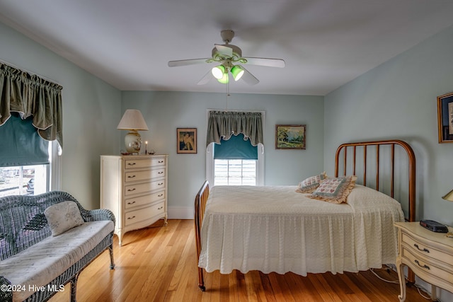 bedroom featuring ceiling fan, light hardwood / wood-style flooring, and multiple windows