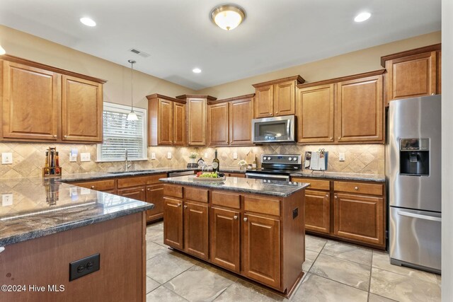 kitchen with decorative light fixtures, dark stone counters, kitchen peninsula, a kitchen island, and stainless steel appliances