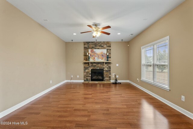 unfurnished living room with hardwood / wood-style flooring, ceiling fan, and a fireplace