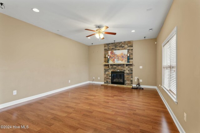 unfurnished living room featuring ceiling fan, hardwood / wood-style floors, and a fireplace