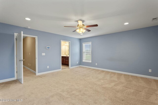 unfurnished bedroom featuring ceiling fan, ensuite bathroom, and light carpet