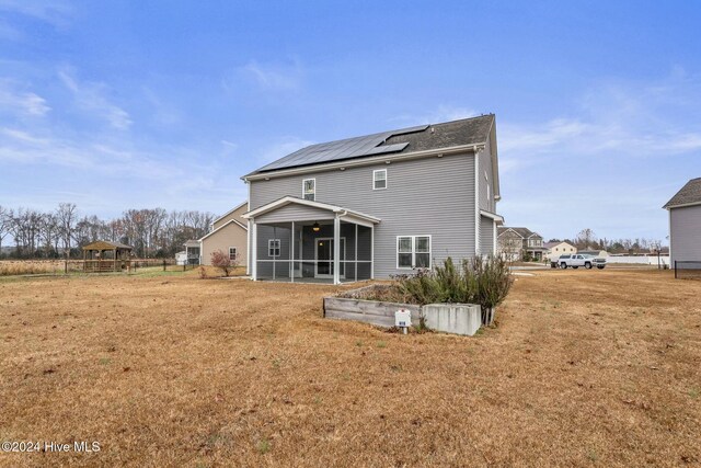 rear view of house with ceiling fan, a patio area, a sunroom, and a lawn