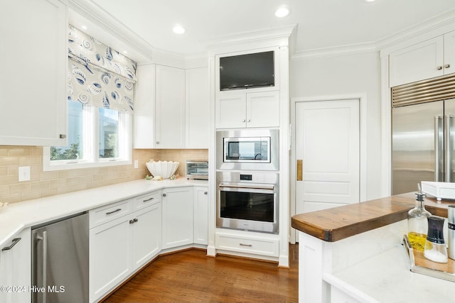 kitchen with white cabinets, decorative backsplash, built in appliances, and dark hardwood / wood-style floors