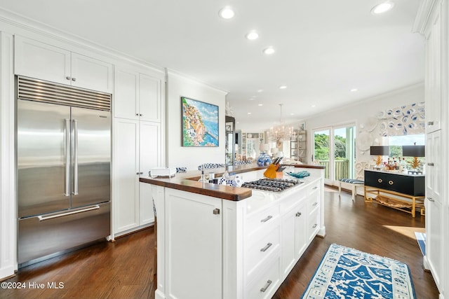 kitchen featuring white cabinetry, dark hardwood / wood-style floors, crown molding, an island with sink, and appliances with stainless steel finishes