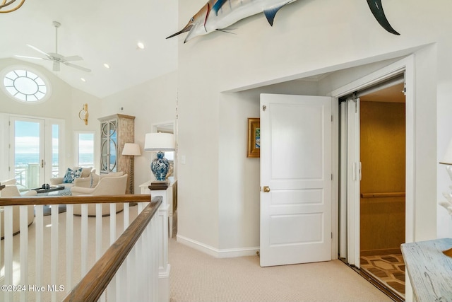 hallway featuring light colored carpet, high vaulted ceiling, and a wealth of natural light