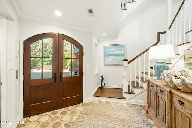 foyer entrance featuring french doors, light wood-type flooring, and crown molding