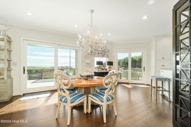 dining area with hardwood / wood-style flooring, plenty of natural light, ornamental molding, and a chandelier