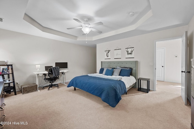 bedroom featuring a raised ceiling, ceiling fan, and light carpet