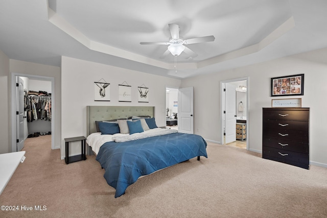 bedroom with a walk in closet, a tray ceiling, ceiling fan, connected bathroom, and a closet