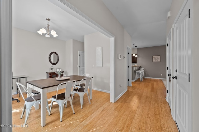 dining room with light hardwood / wood-style floors and an inviting chandelier