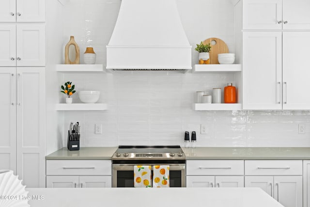 kitchen featuring electric range, decorative backsplash, white cabinetry, and premium range hood