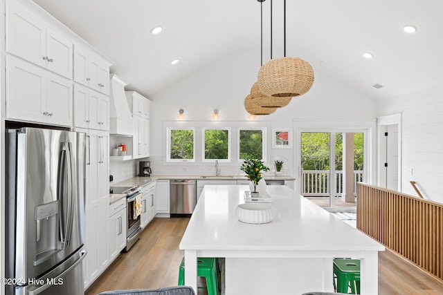 kitchen with stainless steel appliances, white cabinetry, lofted ceiling, and sink