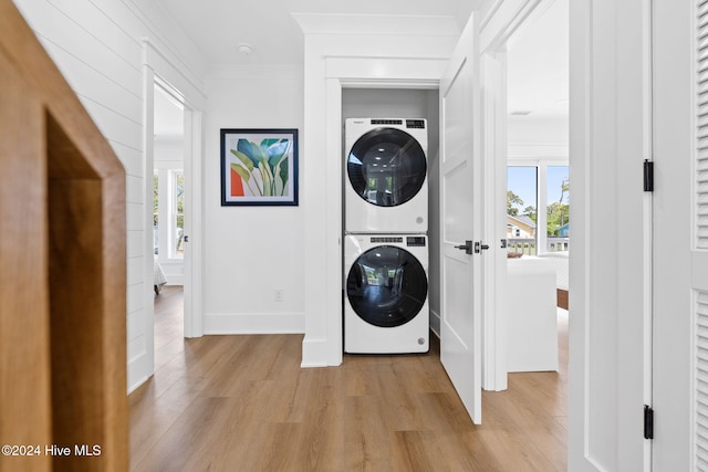 clothes washing area with light hardwood / wood-style floors, crown molding, and stacked washer and clothes dryer