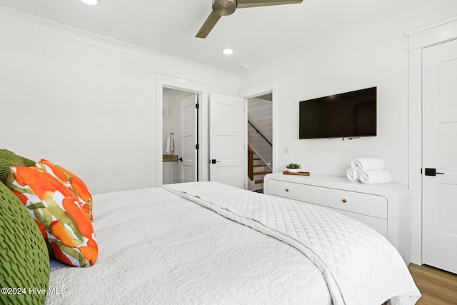 bedroom featuring ensuite bath, ceiling fan, wood-type flooring, and ornamental molding