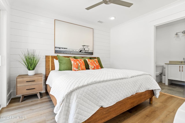 bedroom with ceiling fan, wood walls, and light wood-type flooring