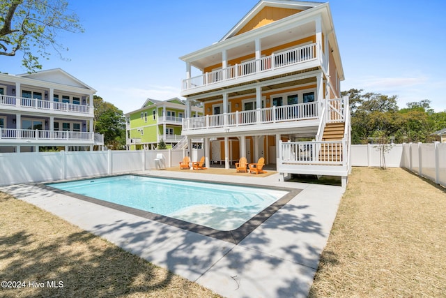 rear view of property featuring a fenced in pool, a balcony, and a patio