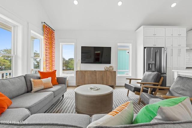 living room with a wealth of natural light, hardwood / wood-style floors, and lofted ceiling