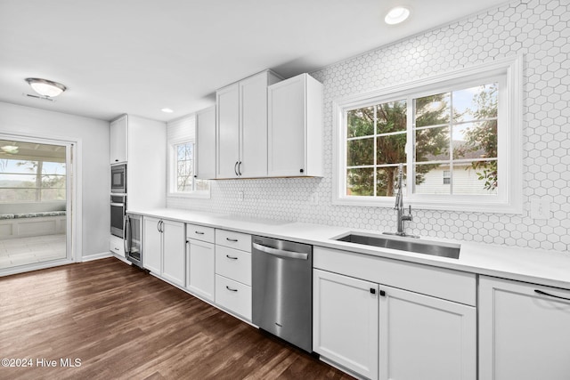 kitchen with sink, dark wood-type flooring, appliances with stainless steel finishes, white cabinetry, and backsplash