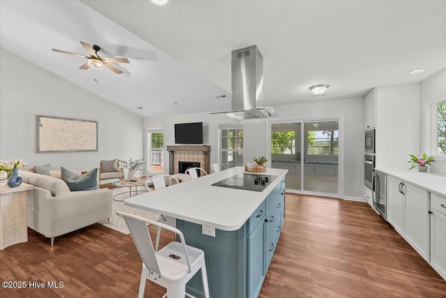 4 Emerald Ln, Pinehurst, NC 28374 - kitchen with island exhaust hood, appliances with stainless steel finishes, a ceiling fan, a breakfast bar area, and a tiled fireplace