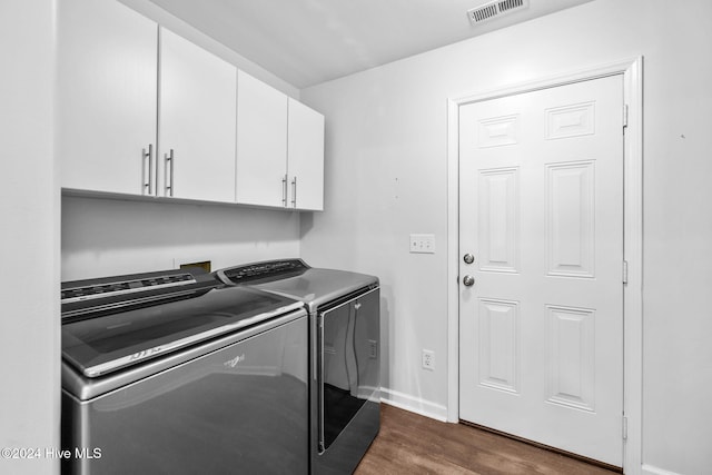 washroom with cabinets, dark hardwood / wood-style flooring, and washer and clothes dryer