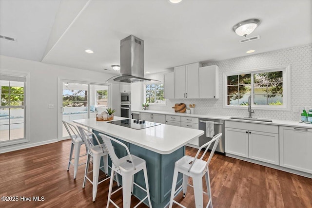 4 Emerald Ln, Pinehurst, NC 28374 - kitchen with stainless steel appliances, island exhaust hood, a sink, a breakfast bar area, and decorative backsplash