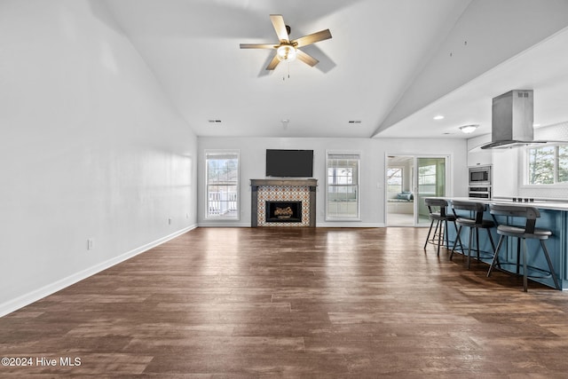 unfurnished living room with plenty of natural light, a tile fireplace, dark hardwood / wood-style floors, and ceiling fan