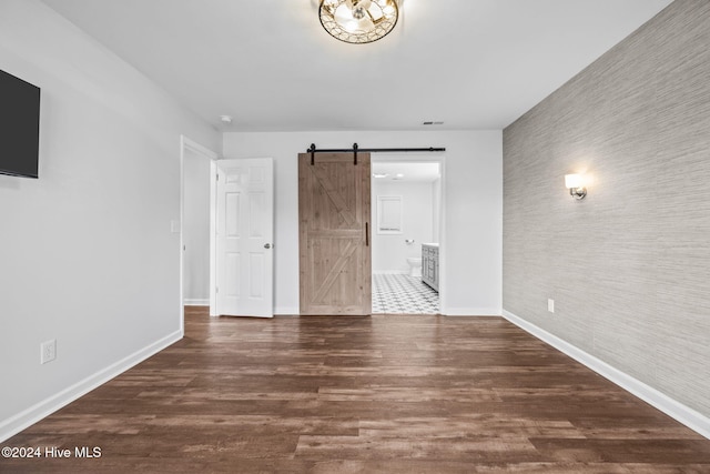 unfurnished room with dark hardwood / wood-style flooring and a barn door