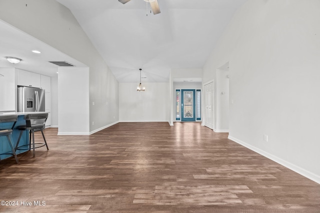 unfurnished living room featuring lofted ceiling, ceiling fan with notable chandelier, and dark wood-type flooring