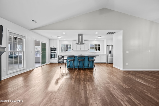 kitchen featuring white cabinetry, island exhaust hood, appliances with stainless steel finishes, and a breakfast bar area