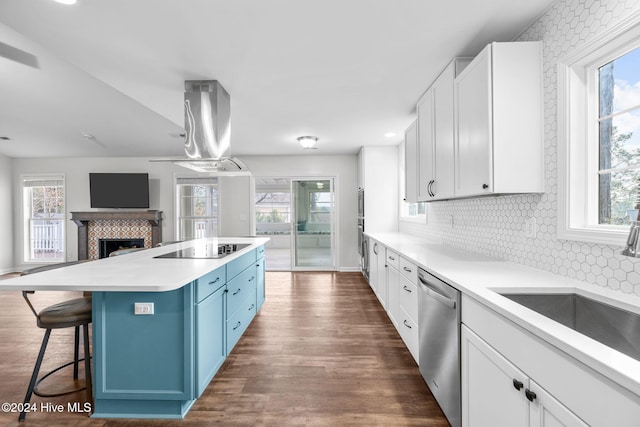 kitchen with sink, white cabinetry, island range hood, a kitchen island, and stainless steel dishwasher