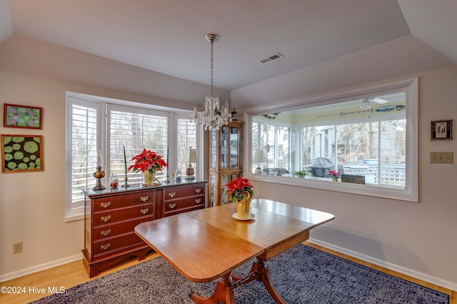 dining area with light wood-type flooring, a wealth of natural light, baseboards, a notable chandelier, and visible vents