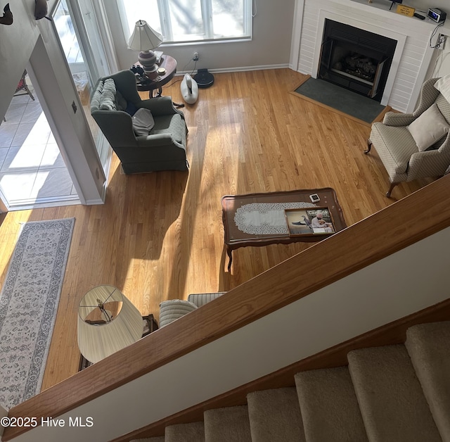 living room with a fireplace with flush hearth, wood finished floors, baseboards, and stairs